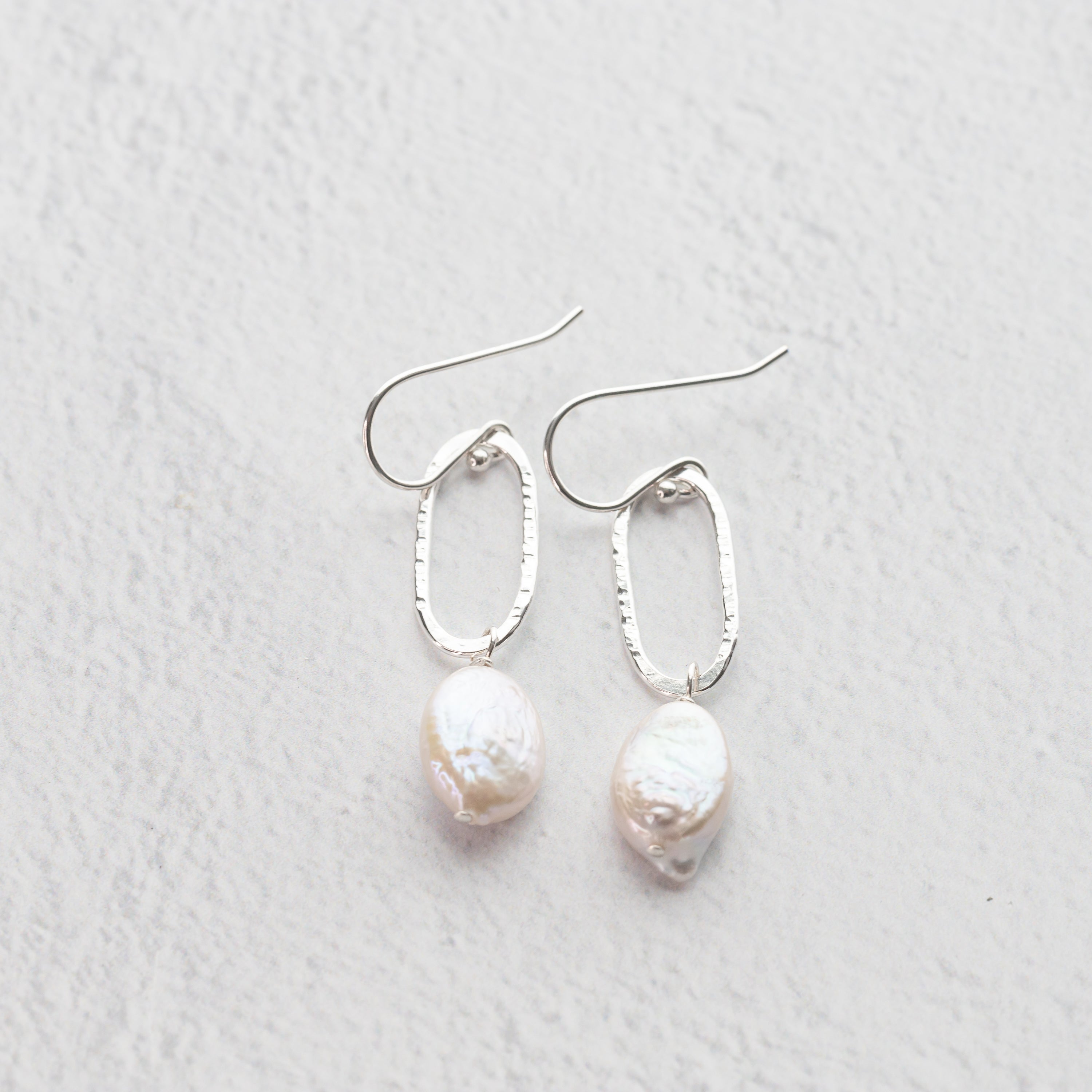 handmade sterling silver and freshwater pearl earrings, hand hammered oval silver dangles drop from nickel free french hook ear wires with lustrous freshater pearl accents.